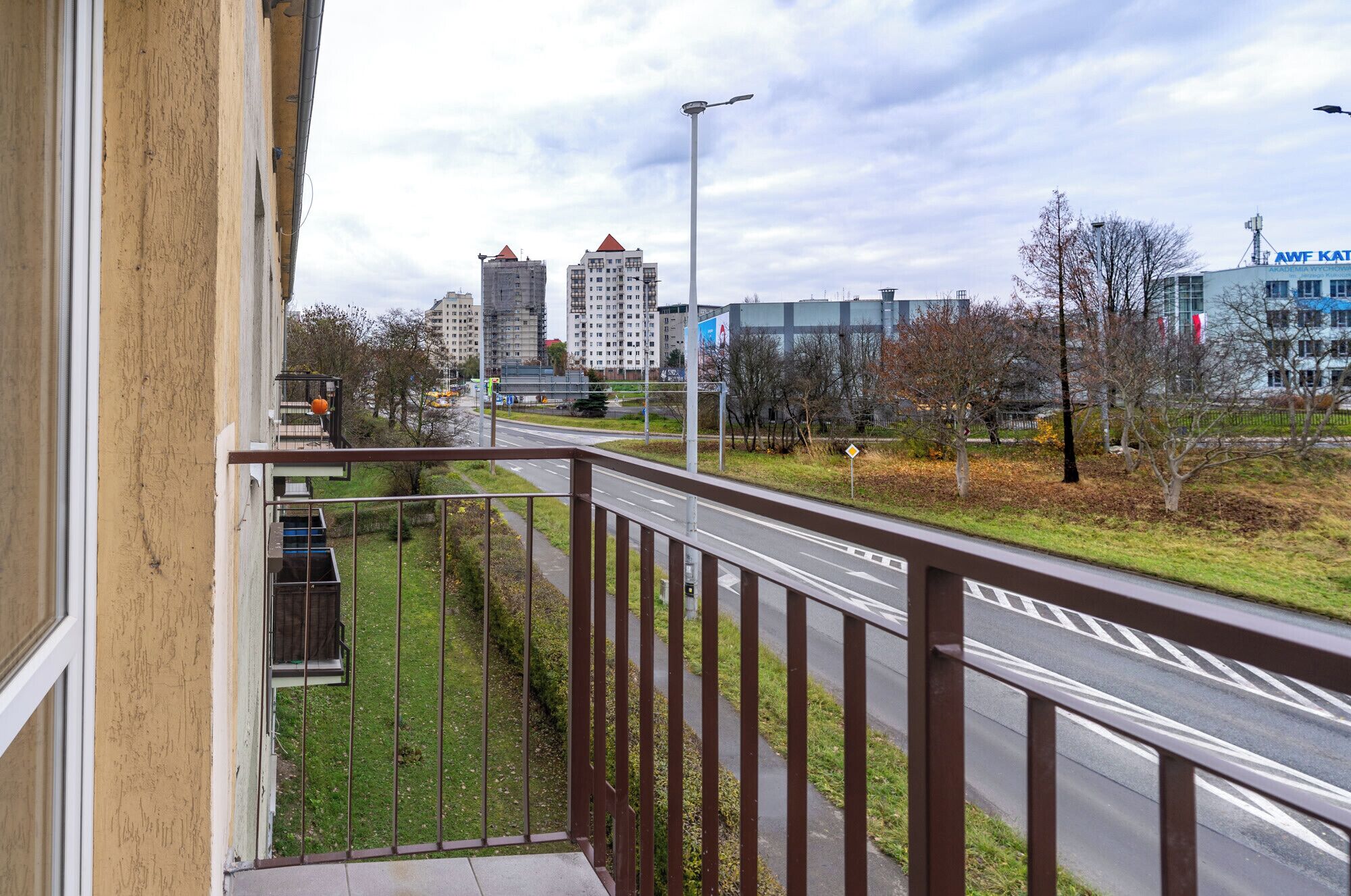 A balcony with a view of a cityscape, including buildings and a road.