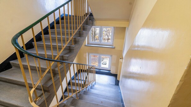 Eine Treppe mit Metallhandlauf und einem Fenster im unteren Bereich.
