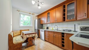 Eine kleine Küche mit Holzausstattung, einem Kühlschrank, einer Mikrowelle und einem Essbereich mit Tisch und Stühlen.