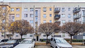 Ein mehrgeschossiges Wohngebäude mit Parkplatz davor.
