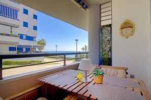 A balcony with a view of the sea, a table with a lamp, and a Buddha statue on the wall. - Wake up to the waves in this beachfront Torrox apartment. (Torrox Costa)