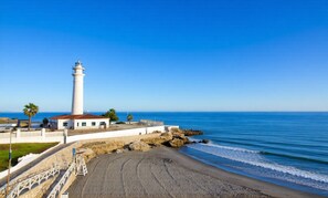 A coastal scene with a lighthouse, beach, and ocean. - Wake up to the waves in this beachfront Torrox apartment. (Torrox Costa)