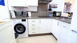 A compact kitchen with a washing machine, microwave, and dishwasher.