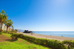 Ein Strand mit einem Gebäude, Palmen und blauem Himmel.