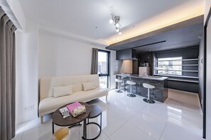 Suite familiar, balcón, vista a la ciudad | Área de sala de estar