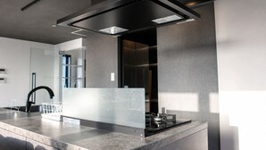 A modern kitchen with a stainless steel countertop, a black faucet, and a built-in range hood. - Osaka Namba River Side Garden Hotel (Osaka)