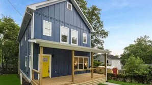 A two-story house with a porch, a yellow door, and a blue exterior.