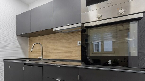Una cocina moderna con horno integrado, microondas y electrodomésticos de acero inoxidable.