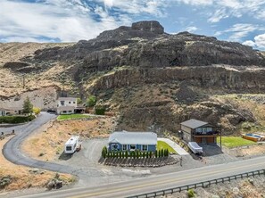 A residential area with houses, a swimming pool, and a large rock formation in the background.