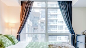 Un lit recouvert d’une couette verte, agrémenté d’un plaid moelleux, et une fenêtre avec des rideaux.