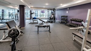 Une salle de sport équipée de matériel d’exercice, d’un téléviseur et offrant une vue sur l’extérieur.