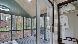 Puinen terassi, jossa on poreallas, lasiovi, joka johtaa metsäiselle alueelle, ja pyyheille tarkoitettu teline.