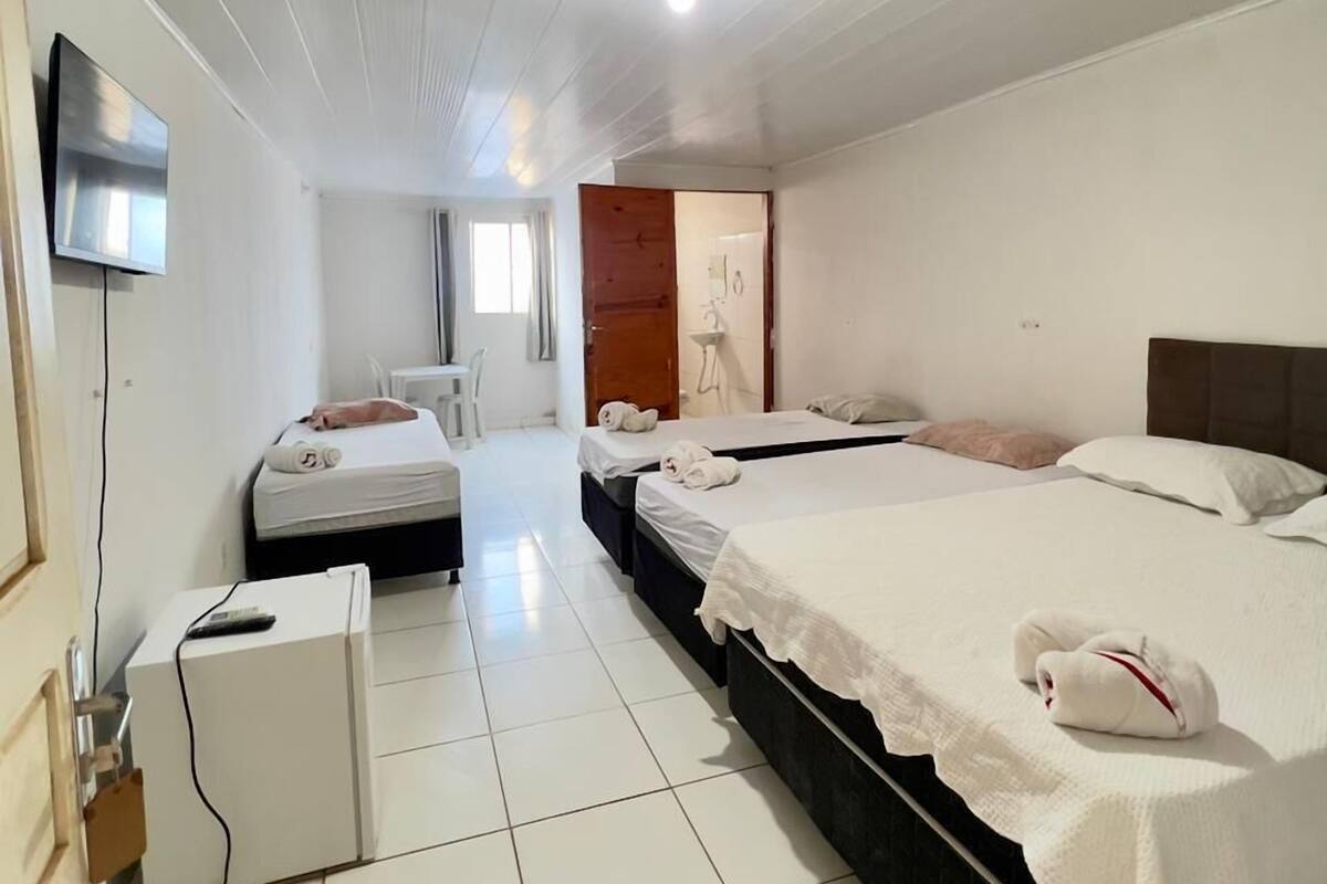 A hotel room with two beds, a TV, a desk, and a bathroom visible through an open door.