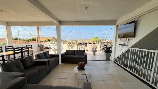 A covered outdoor seating area with sofas, a coffee table, and a TV mounted on the wall. - Pousada Rancho do Sabiá (Baraúna)