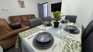 Un coin repas avec un canapé en cuir marron, une table à manger dressée avec des assiettes, des verres et une plante en pot.