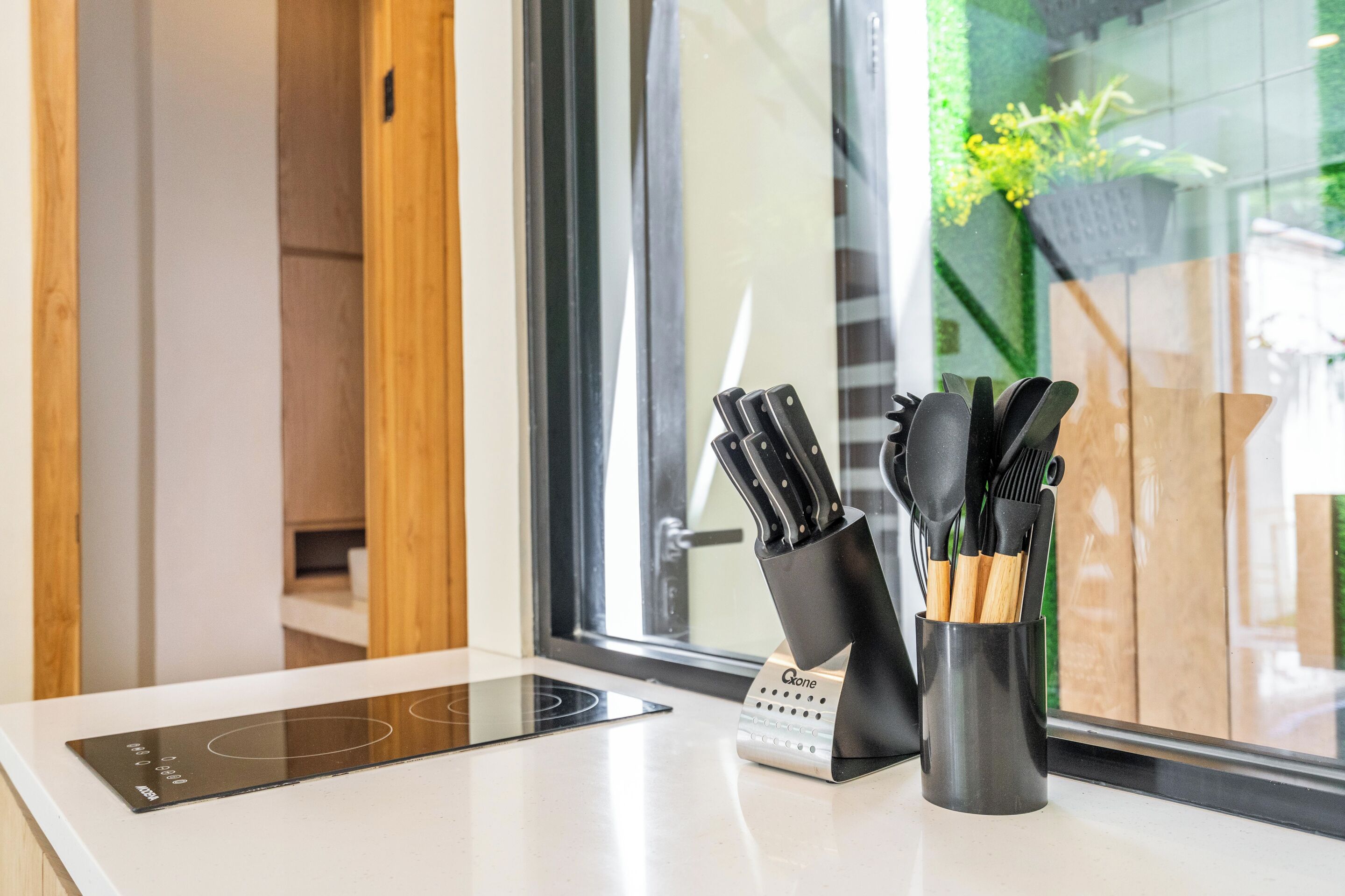 A kitchen counter with a modern induction cooktop, a knife block, and a digital scale.