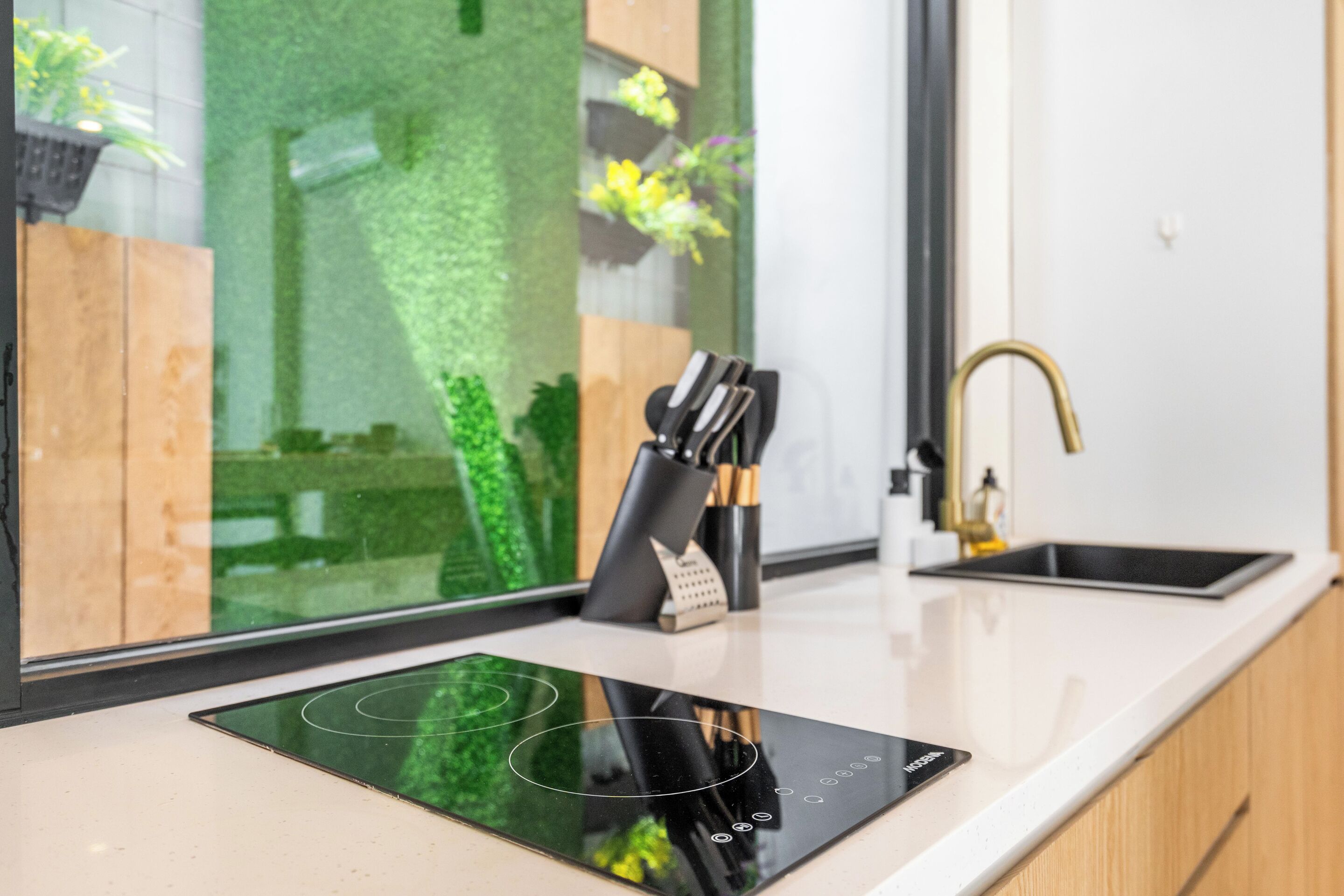 A modern kitchen with a built-in induction cooktop, a knife block, and a sink.