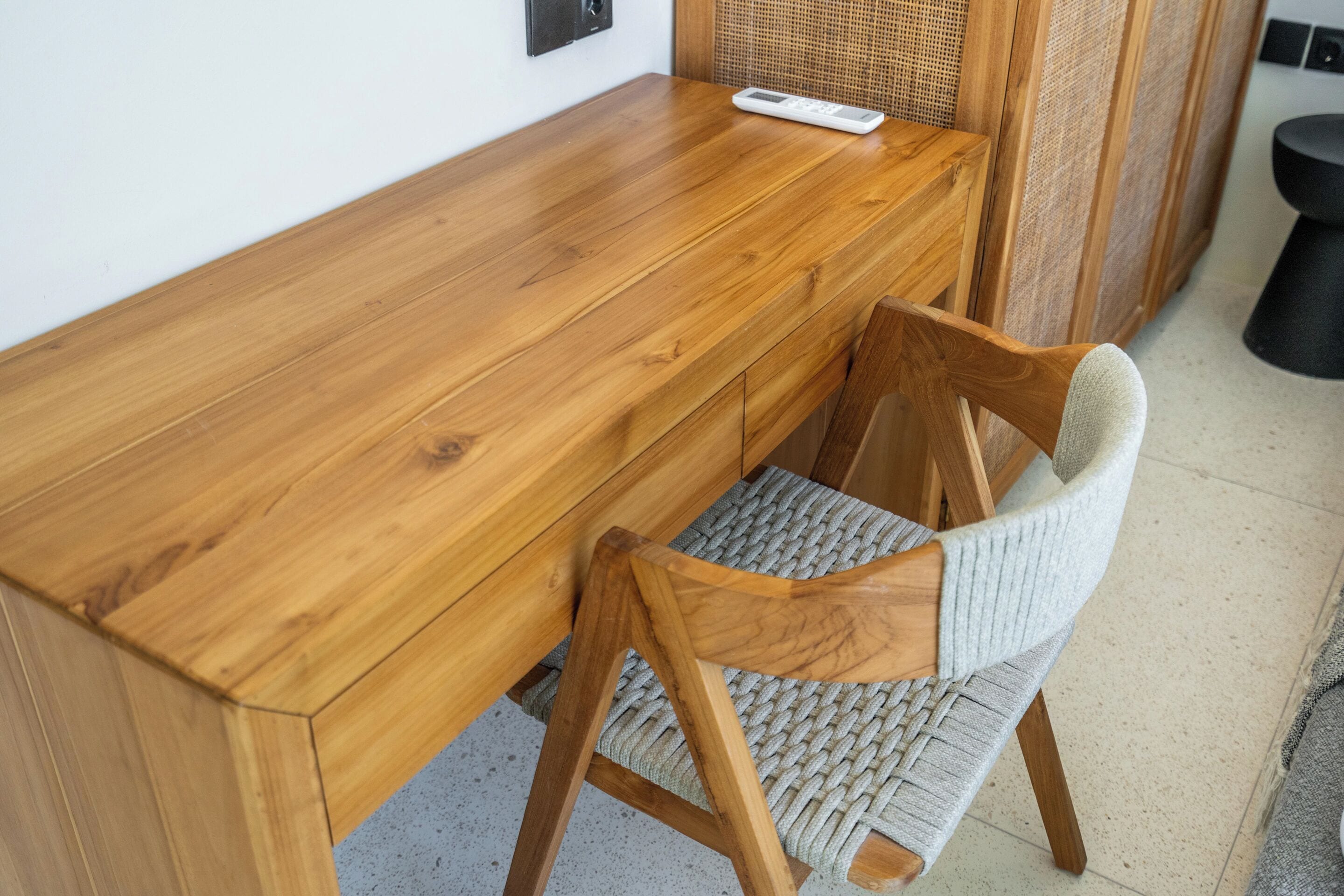 A wooden dining table with a woven chair in front.