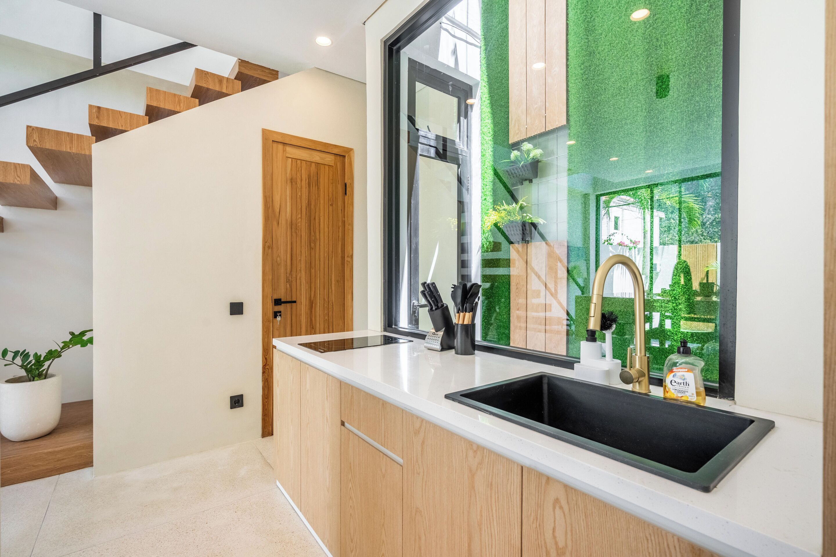 Une cuisine moderne dotée d’une grande fenêtre, de meubles en bois et d’un évier encastré.