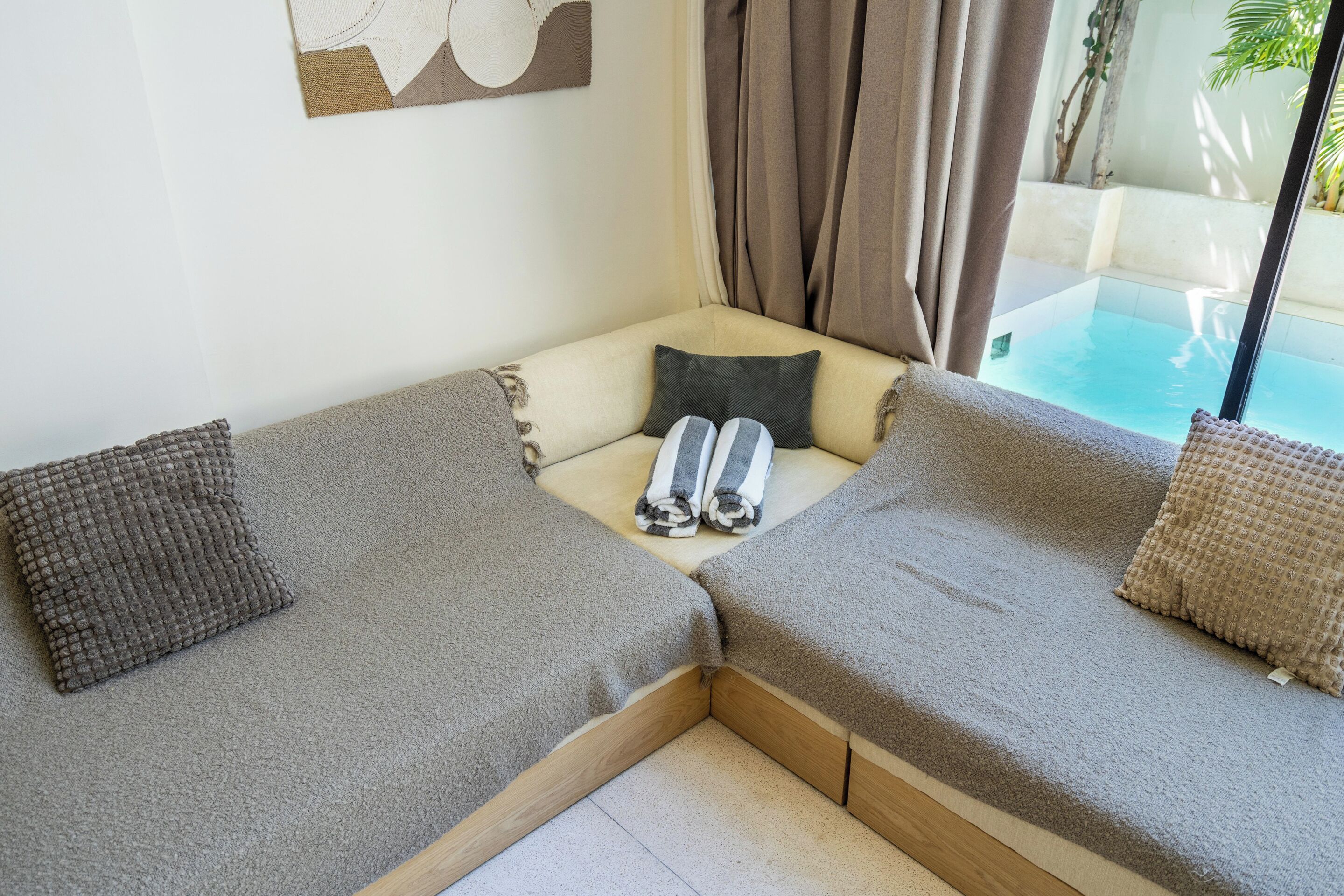 A corner sofa with a cushion, a pillow, and a rolled towel.