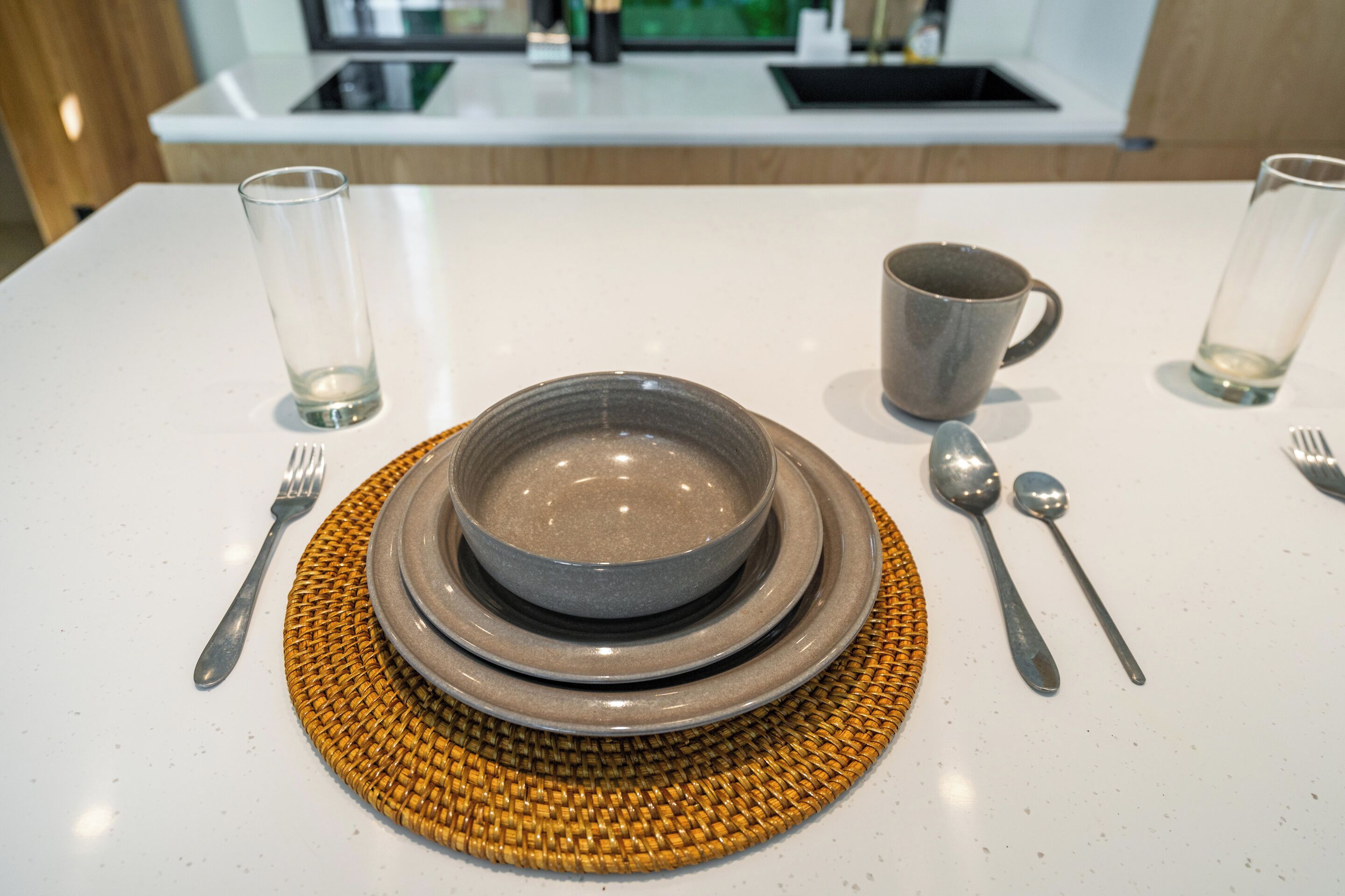 A table set with a bowl, plates, cutlery, and glasses.
