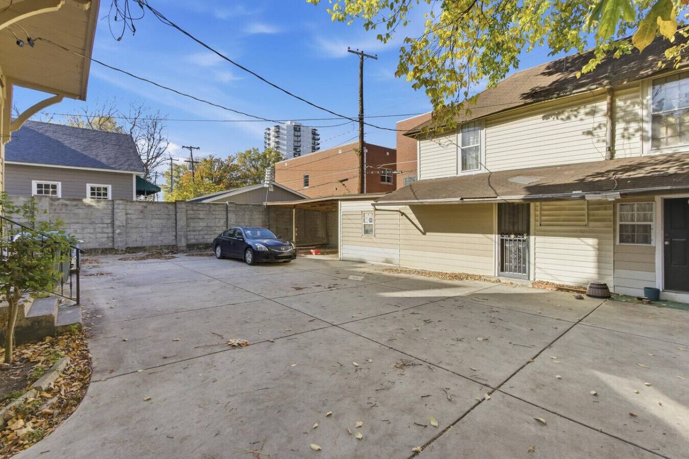 A residential driveway with a parked car, a garage, and a house with a brick facade.