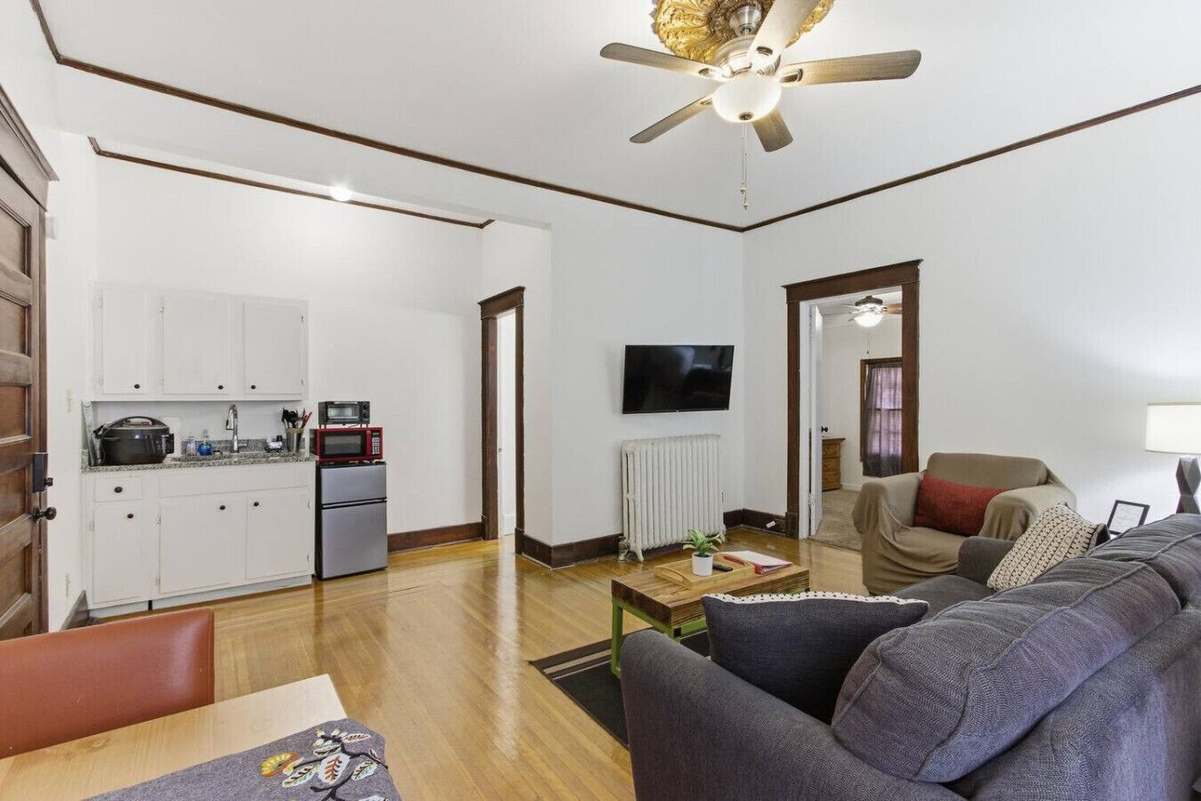 Een knus woongedeelte met een kitchenette, een bank, een salontafel en een plafondventilator.