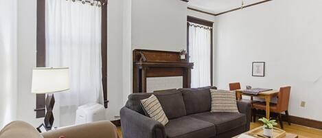 A living room with a sofa, armchairs, a coffee table, a fireplace, and a dining area with a table and chairs.