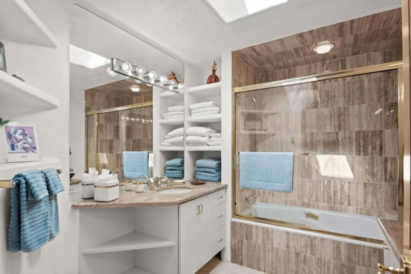 Un baño moderno con tocador, un espejo grande, ducha con puerta de vidrio y un perchero para toallas.