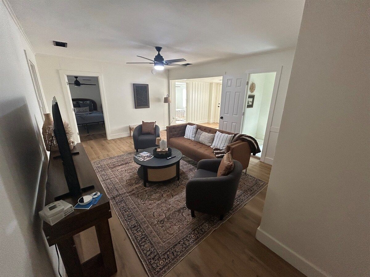 Sala de estar com sofá, poltronas, mesa de centro e televisão.