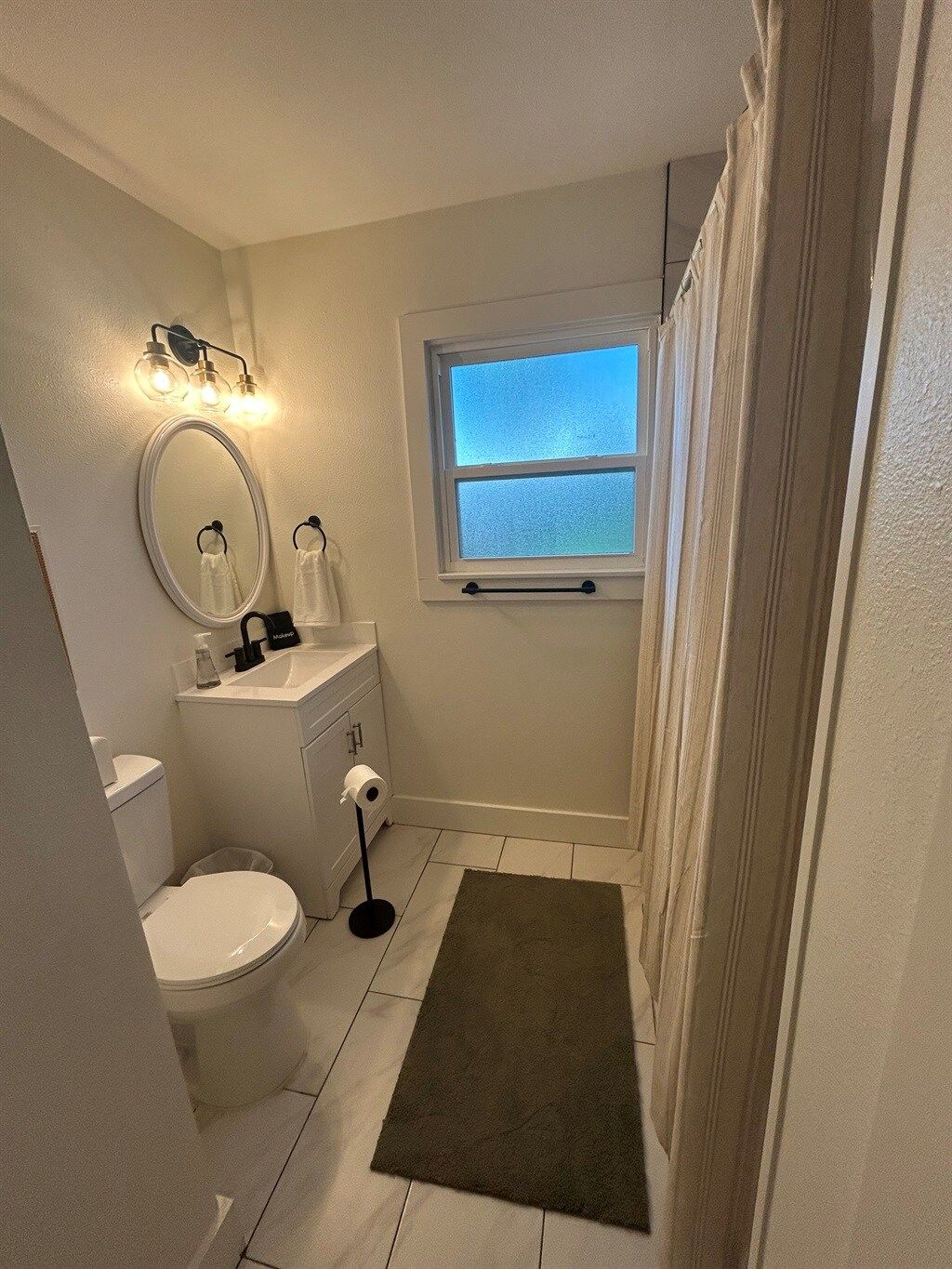 Een badkamer met toilet, wastafel, spiegel en raam.