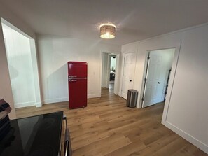 A hallway with a red refrigerator, a trash can, and a door leading to another room. - Wildcat Way! 4 Bedrooms | Games! Steps from ACU! (Abilene)