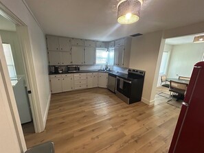 A kitchen with white cabinets, a black stove, and a dining area with a table and chairs.