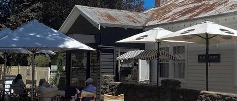 An outdoor seating area with wooden chairs and umbrellas, a stone wall, and a building with a sign reading "MARC STREET".