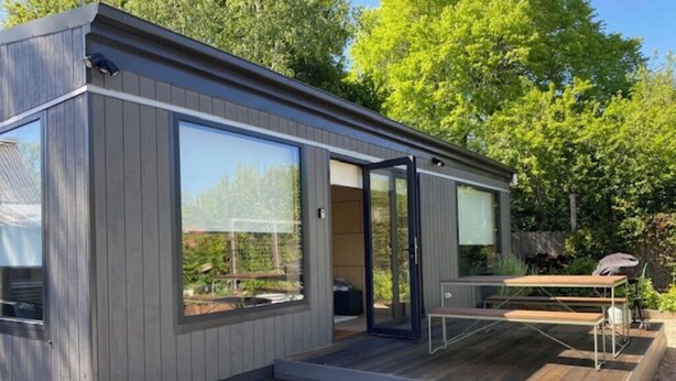 Et moderne, kompakt hus med store vinduer og en terrassemiljø.