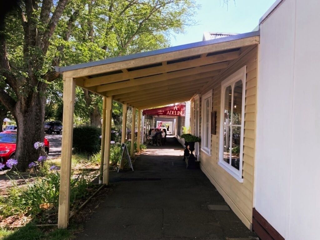 A covered walkway leading to a building with a sign that reads "ADELINA".