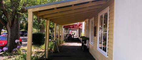 A covered walkway leading to a building with a sign that reads "ADELINA".
