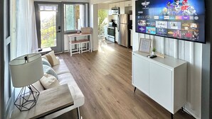 Een moderne woonkamer met een flatscreen televisie, een bank en een eethoek.