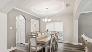 A dining area with a wooden table and chairs, a chandelier, and a view of the outdoors. - Spacious 6BR Villa for 14 · Home Theater, Game Loft & Gym · 10 Min to Universal (McKinney)
