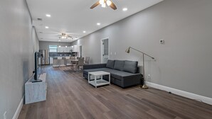 Ein modernes Wohnzimmer mit einem grauen Sofa, einem Couchtisch und einem Deckenventilator.