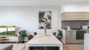Cozinha moderna com área de jantar, televisão de tela plana e um quadro na parede.