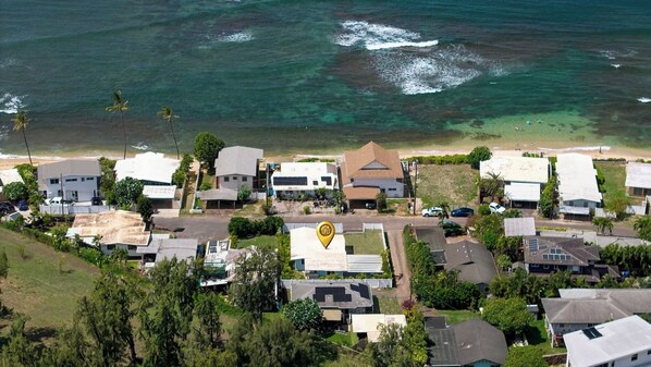 A coastal residential area with houses, a road, and a beach.