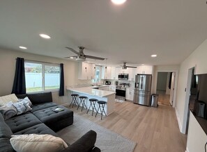 A modern kitchen with a central island, stainless steel appliances, and a ceiling fan.