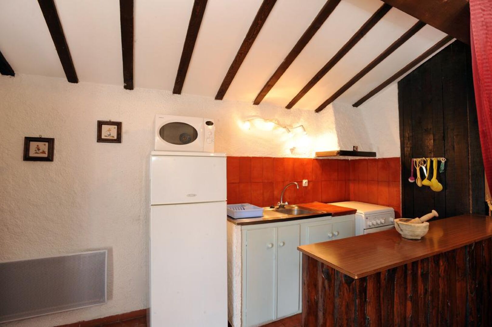 Eine kleine Küche mit einem weißen Kühlschrank, einer Spüle und Holzschränken.