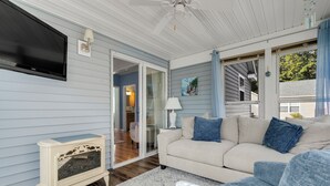 Un salon avec un canapé beige, un téléviseur et un ventilateur de plafond.