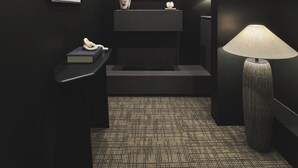 A dimly lit room with a framed photograph on the wall, a small table with a book and a decorative object, a floor lamp, and a television screen displaying a person. - Guwol Hotel Jongno Ikseon (Seoul)