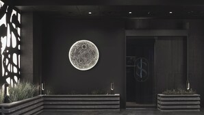 A modern interior with a circular moon-like artwork on the wall, a dark-toned reception desk, and a minimalist design. - Guwol Hotel Jongno Ikseon (Seoul)