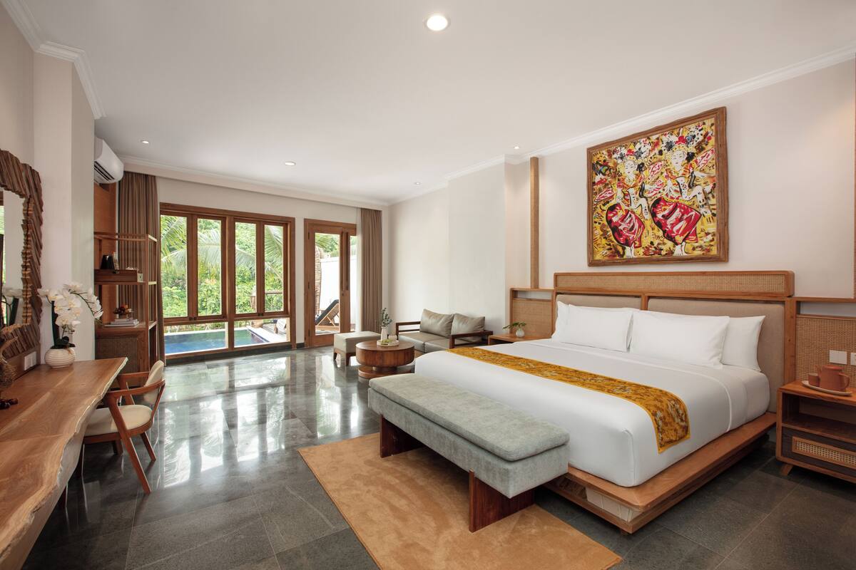 A spacious bedroom with a large bed, a desk, and a view of the outdoors.