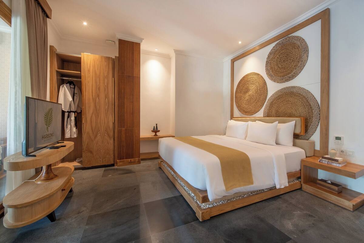 A modern hotel room with a large bed, wooden furniture, a TV, and a wardrobe.