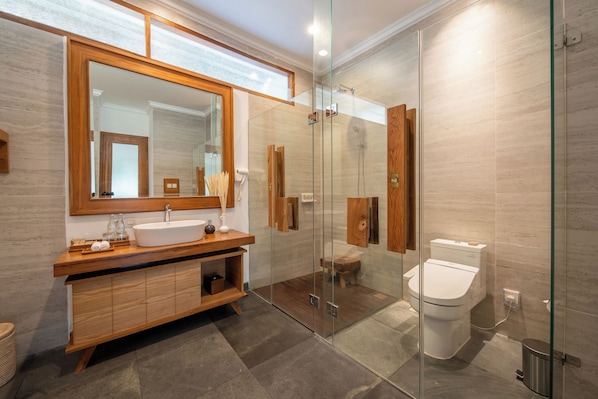 A modern bathroom with a glass-enclosed shower, a wooden vanity, and a large mirror. - Harsono Boutique Resort Bali (Batubulan)